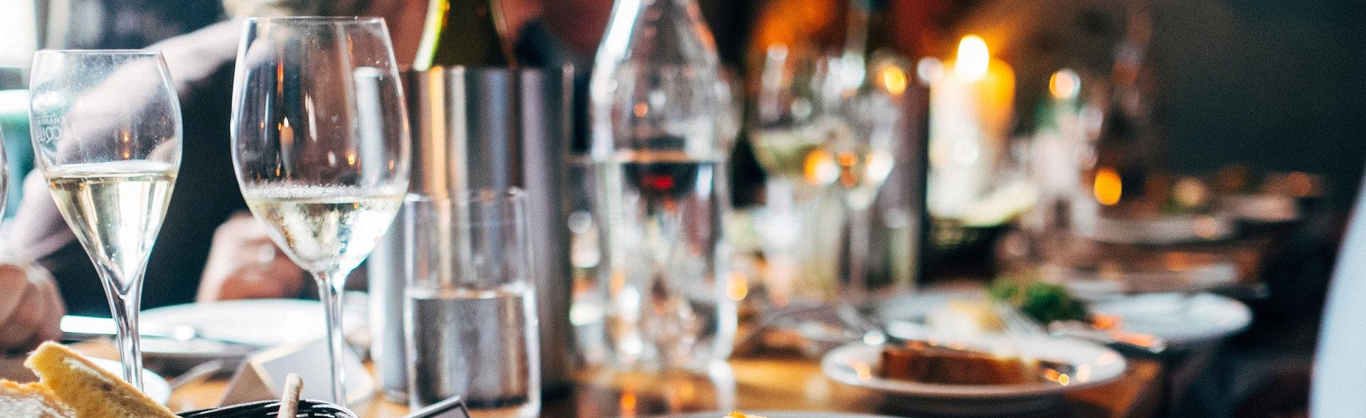 Une table dressée avec du vin devant des silhouettes floues chez Etna Rosso